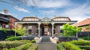 A Victorian-style house with a prominent front porch, a brick facade, and a symmetrical design. - Cappa House, Kew by Property Mums (Kew)