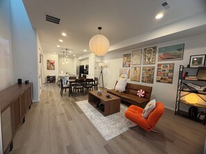 A modern living room with a dining area, wooden flooring, and a large window. - Modern 3B/2.5BA Townhouse in East Colorado Springs (Colorado Springs)