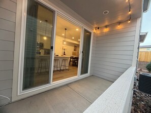 A covered patio with a sliding glass door leading to a kitchen area. - Modern 3B/2.5BA Townhouse in East Colorado Springs (Colorado Springs)