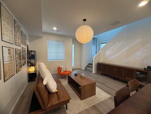 A modern living room with a sofa, coffee table, and a large screen displaying a mountain landscape. - Modern 3B/2.5BA Townhouse in East Colorado Springs (Colorado Springs)