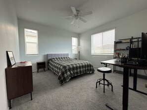 A bedroom with a bed, a desk, a chair, a ceiling fan, and a bookshelf. - Modern 3B/2.5BA Townhouse in East Colorado Springs (Colorado Springs)