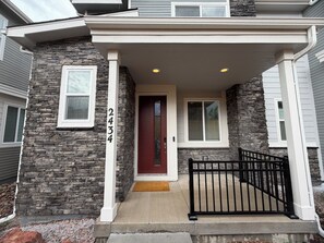 A residential house with a stone facade, a red door, and a black metal gate. - Modern 3B/2.5BA Townhouse in East Colorado Springs (Colorado Springs)