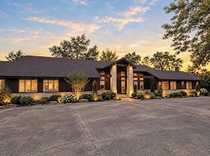 A modern two-story building with a stone facade, large windows, and a spacious driveway.