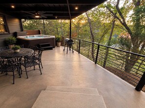 An outdoor patio with a hot tub, grill, and seating area.