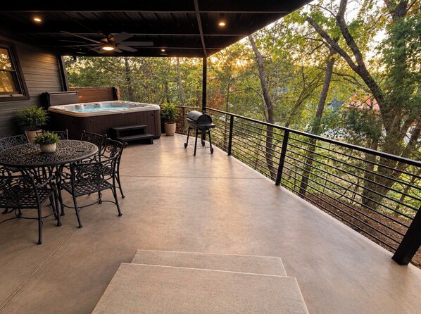 An outdoor patio with a hot tub, grill, and seating area.