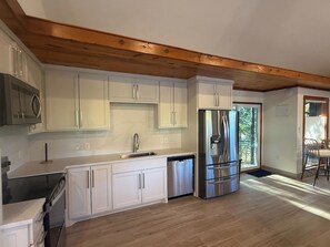 A modern kitchen with white cabinetry, stainless steel appliances, and a wooden ceiling. - Lakehouse Escape - Hot Tub - Fire Pit  - Eureka Springs (Eureka Springs)