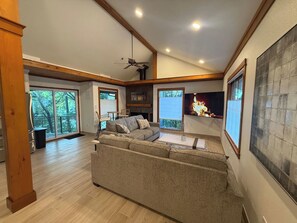 A spacious living room with a large sectional sofa, a fireplace, and a television. - Lakehouse Escape - Hot Tub - Fire Pit  - Eureka Springs (Eureka Springs)