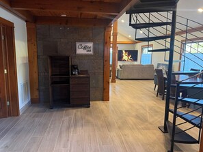 A spacious interior with a stone fireplace, a coffee bar sign, and a staircase.
