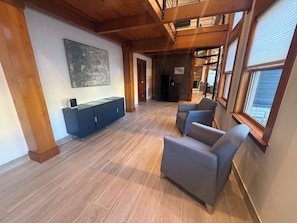 A spacious room with a wooden floor, a blue cabinet, and grey armchairs.