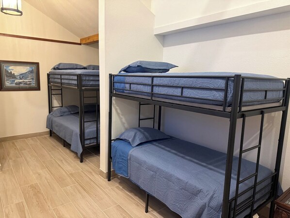 A bunk bed room with a framed picture on the wall and a wooden floor.