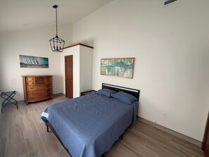 A bedroom with a bed, wooden dresser, and artwork on the walls. - Eureka Springs Lake Lodge sleeps 14 - Hot Tub (Eureka Springs)