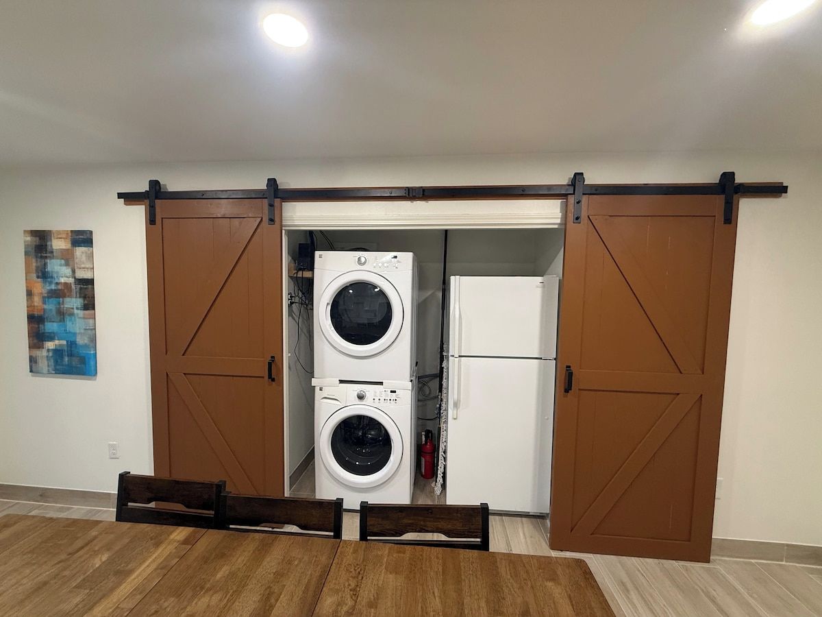 A laundry room with two stacked washing machines and a refrigerator.