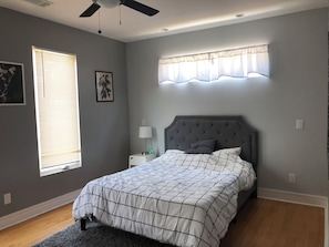 A bedroom with a bed, a nightstand, a ceiling fan, a window with blinds, and a wall-mounted lamp. - Stylish Grant Park Home Minutes from Downtown Atlanta perfect for your getaway (Atlanta)