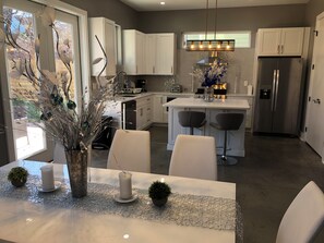 A modern kitchen with white cabinets, a central island with bar stools, and a stainless steel refrigerator. - Stylish Grant Park Home Minutes from Downtown Atlanta perfect for your getaway (Atlanta)