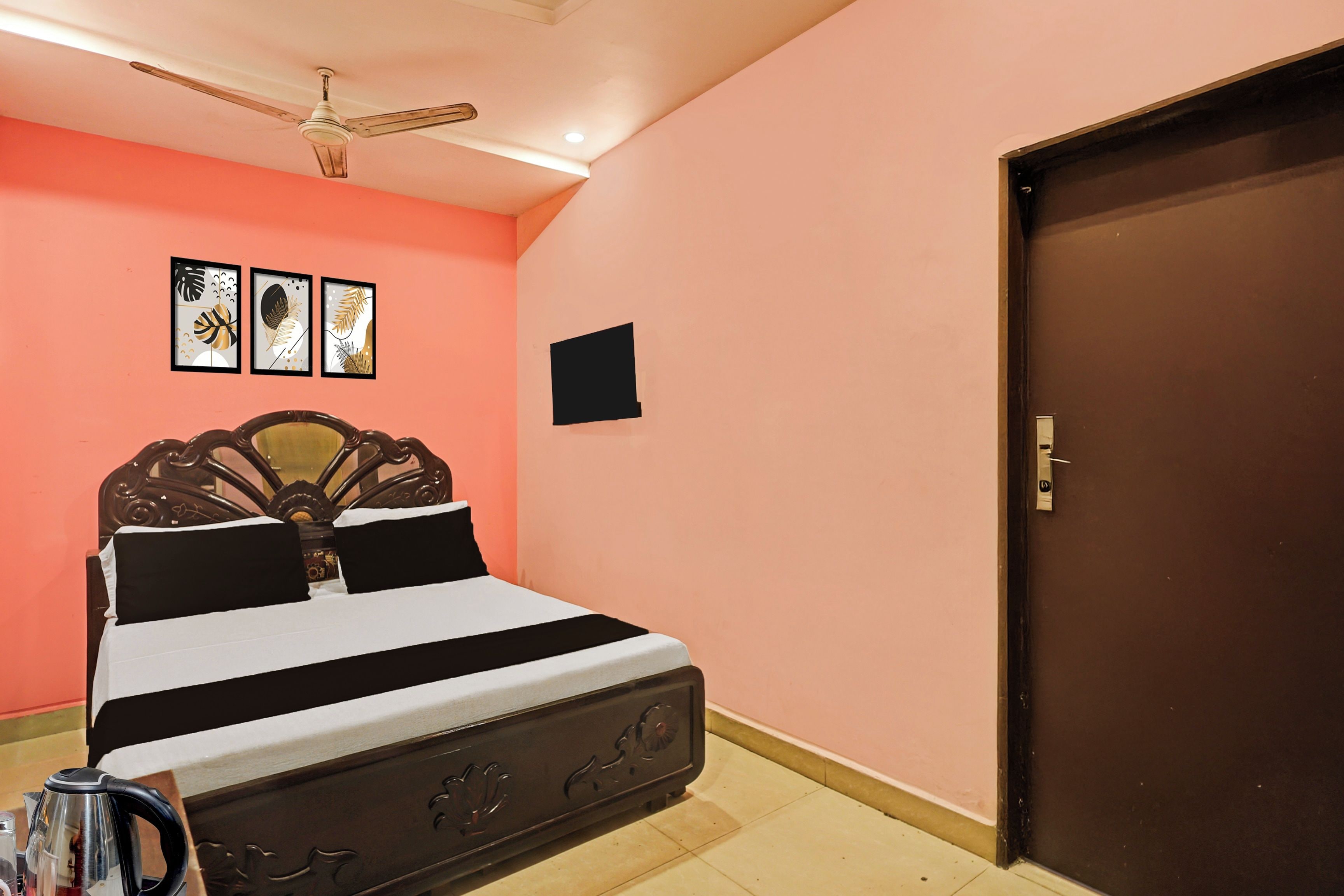 A bedroom with a bed, a ceiling fan, a door, and wall-mounted pictures.