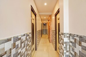 A hallway with patterned tile walls and a tiled floor, leading to a door at the end. - Hotel O Vizag Centre Formerly Sri SaiInn (Visakhapatnam)