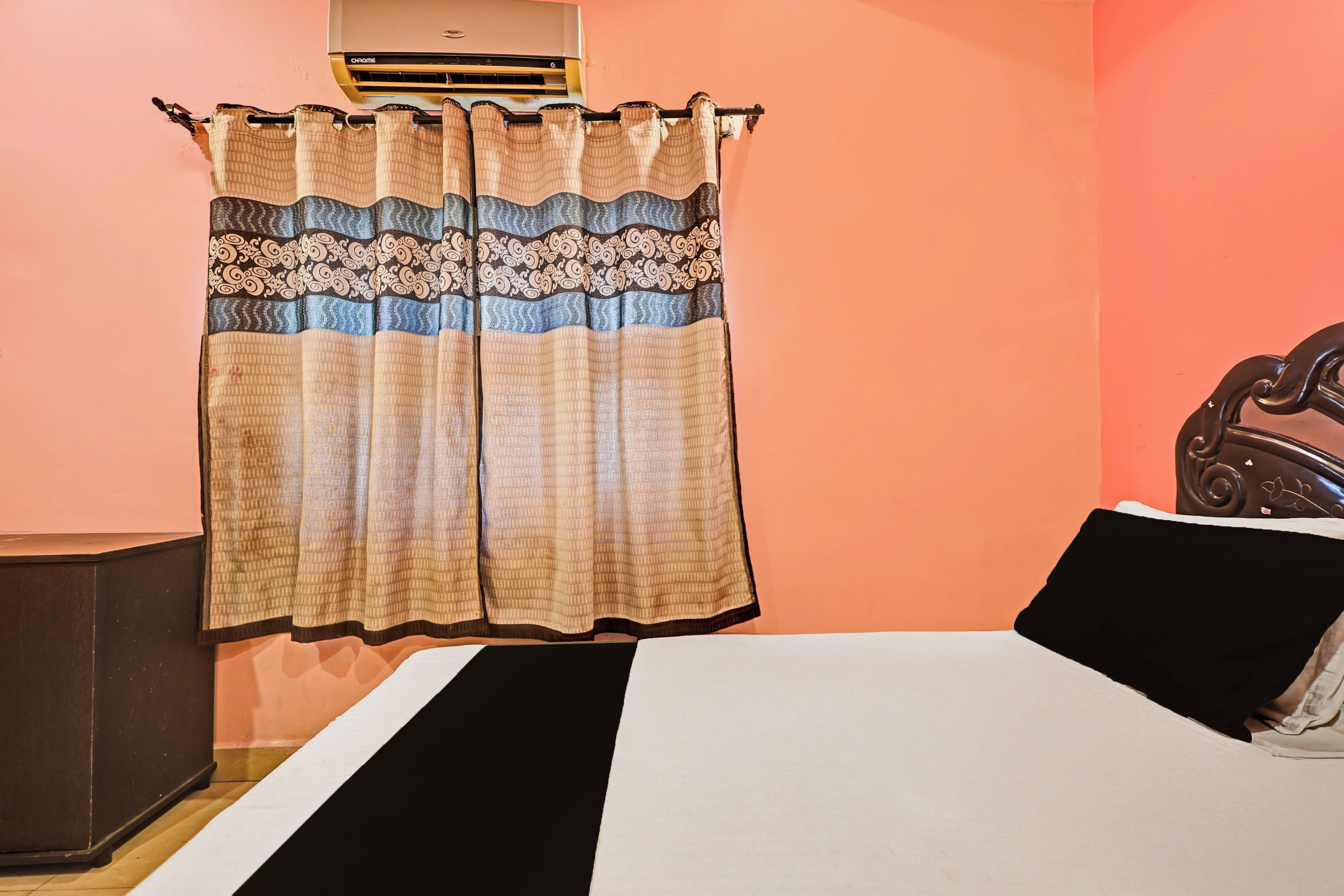 Un dormitorio con cama, mesita de noche, cómoda y ventana con cortinas.