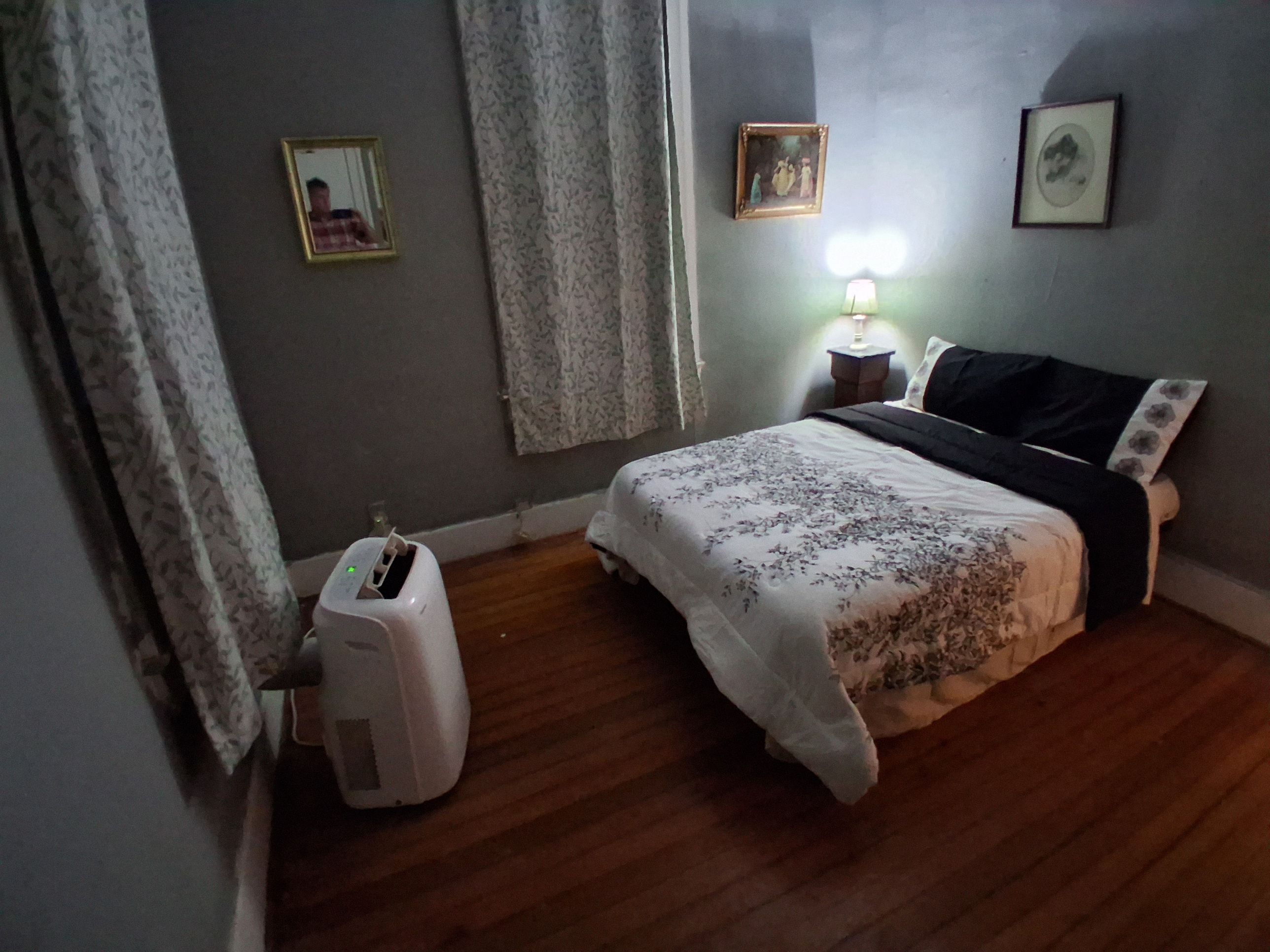 Un dormitorio con cama, lámpara de noche y un calefactor en el suelo.