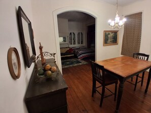 Ein Essbereich mit Holztisch und Stühlen, einer Chandelüster und einem Spiegel an der Wand.