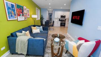 A modern living room with a sectional sofa, a coffee table, and a TV mounted on the wall.