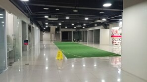 A corridor with a green carpet, glass doors, and a sign indicating a store. - Cozy 1-bedroom Apartment in Delightful Quezon City with AC (Quezon City)