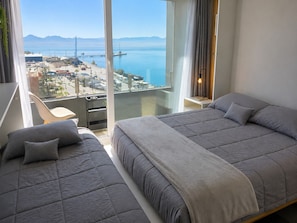 Una habitación de hotel moderna con dos camas, un balcón con vistas a la ciudad y un ventanal grande.