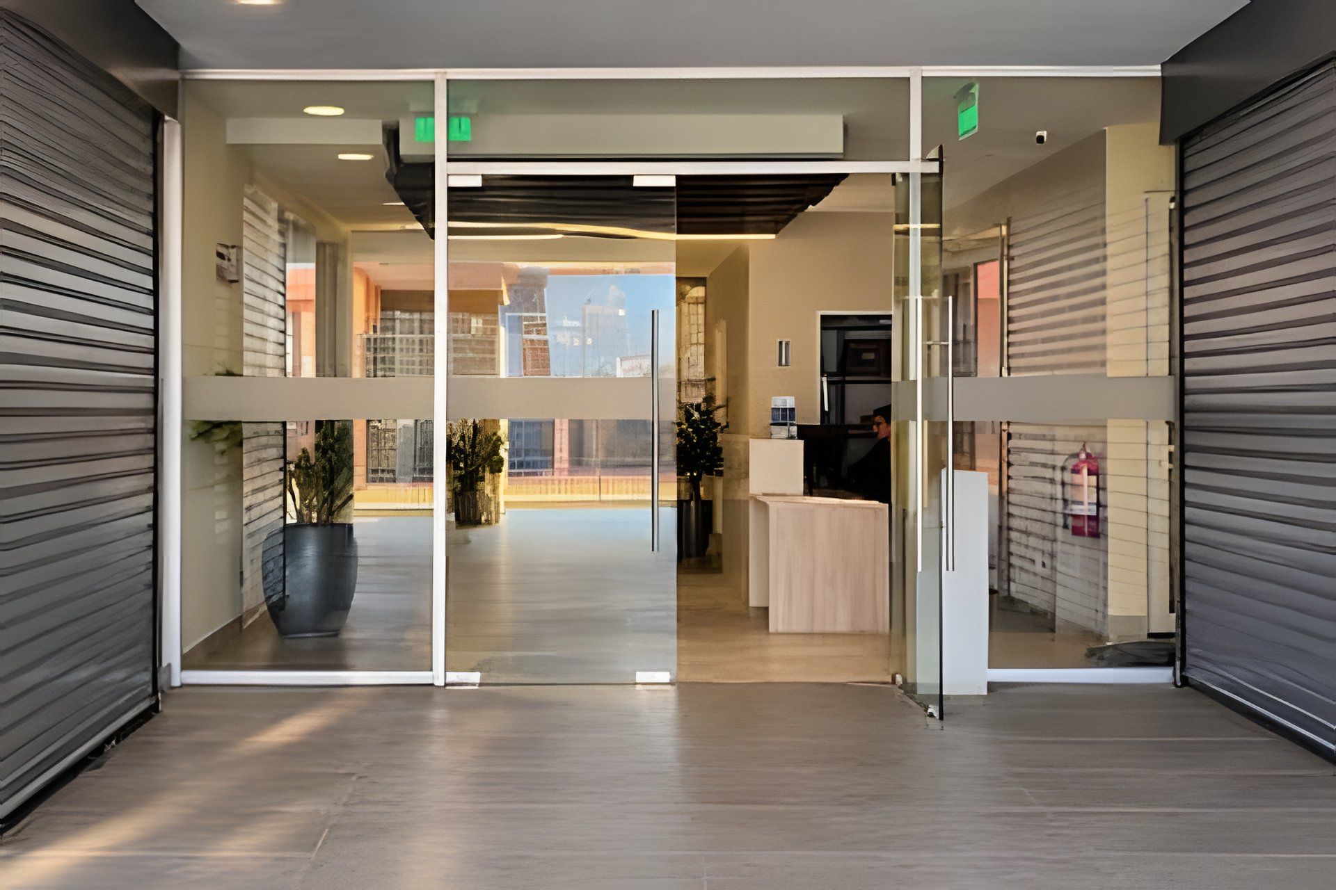 A modern reception area with a glass partition, a reception desk, and a view of the cityscape through the glass.