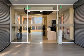 A modern reception area with a glass partition, a reception desk, and a view of the cityscape through the glass. - Vista al mar - Estudio para 3 personas (Coquimbo)