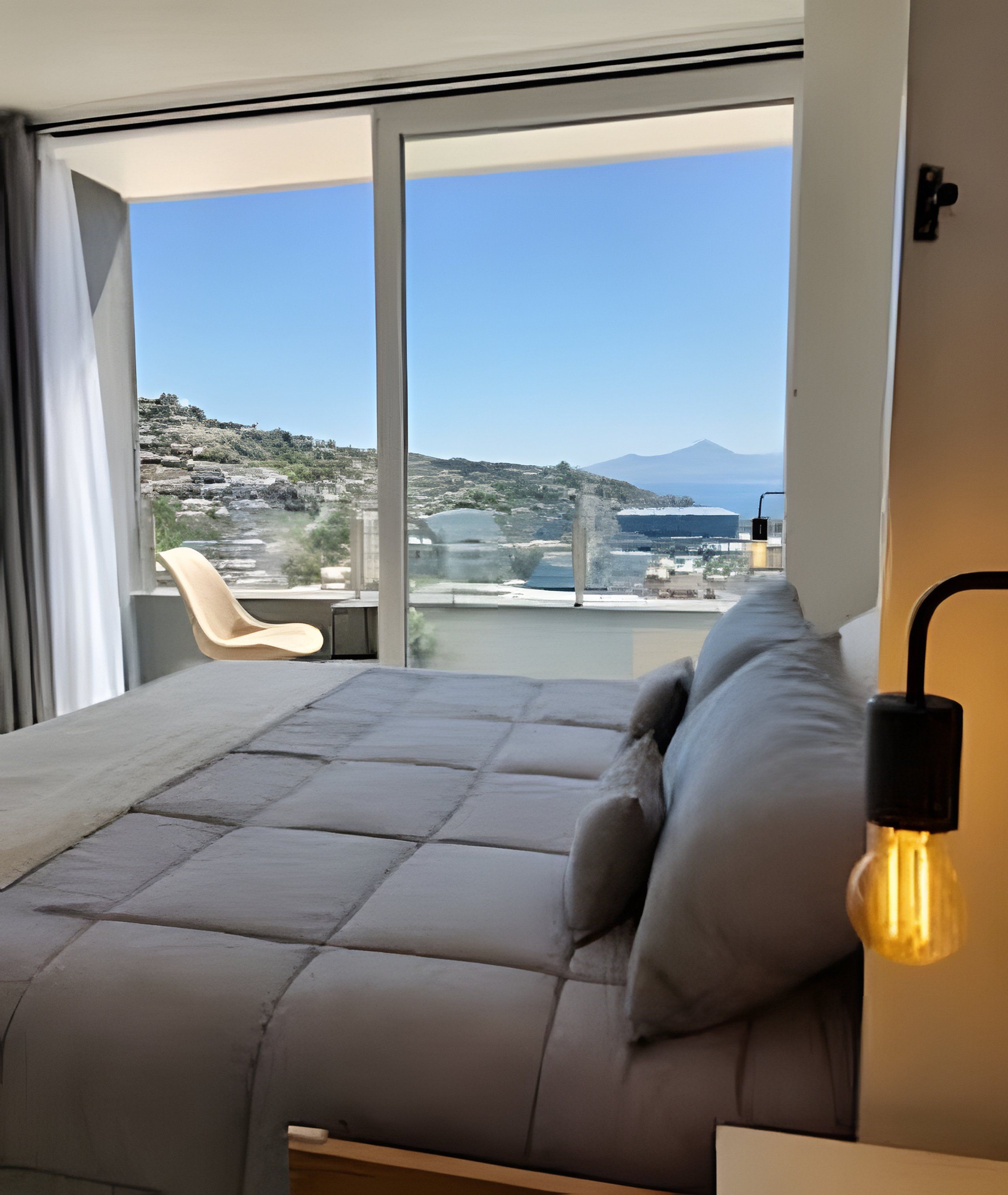 Quarto moderno com uma janela grande, um sofá e uma cadeira.