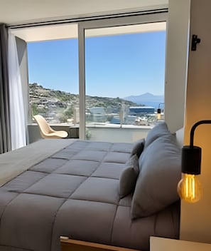 Un dormitorio moderno con un ventanal grande, un sofá y una silla.