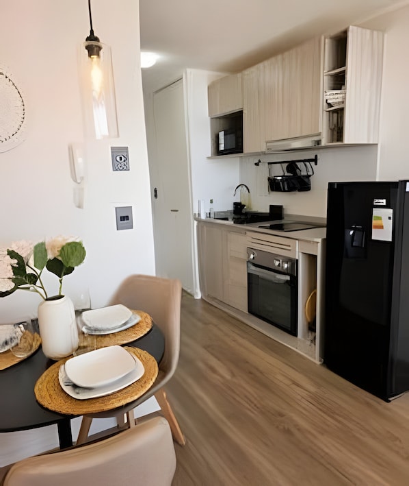 A modern kitchen with a dining area, including a table with plates and a vase of flowers.