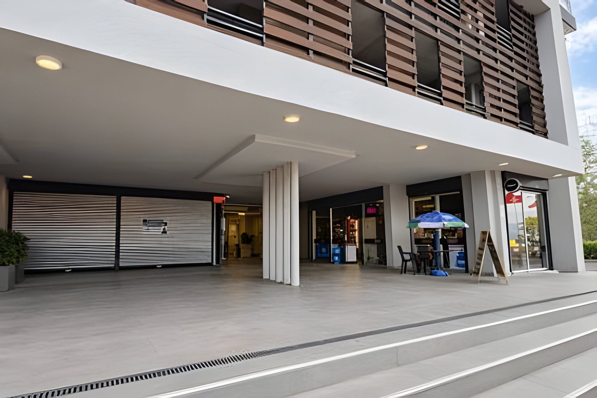 Een modern gebouw met een overdekte ingang, grote ramen en een trap.
