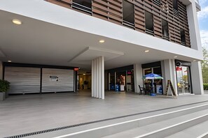 Un edifici modern amb entrada coberta, grans finestres i una escala que puja.