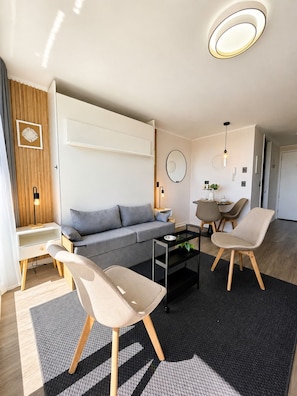 A modern living room with a sofa, two chairs, a coffee table, and a dining area with a table and chairs.