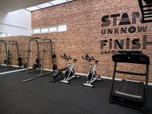 A gym with brick walls, various exercise equipment, and motivational text.