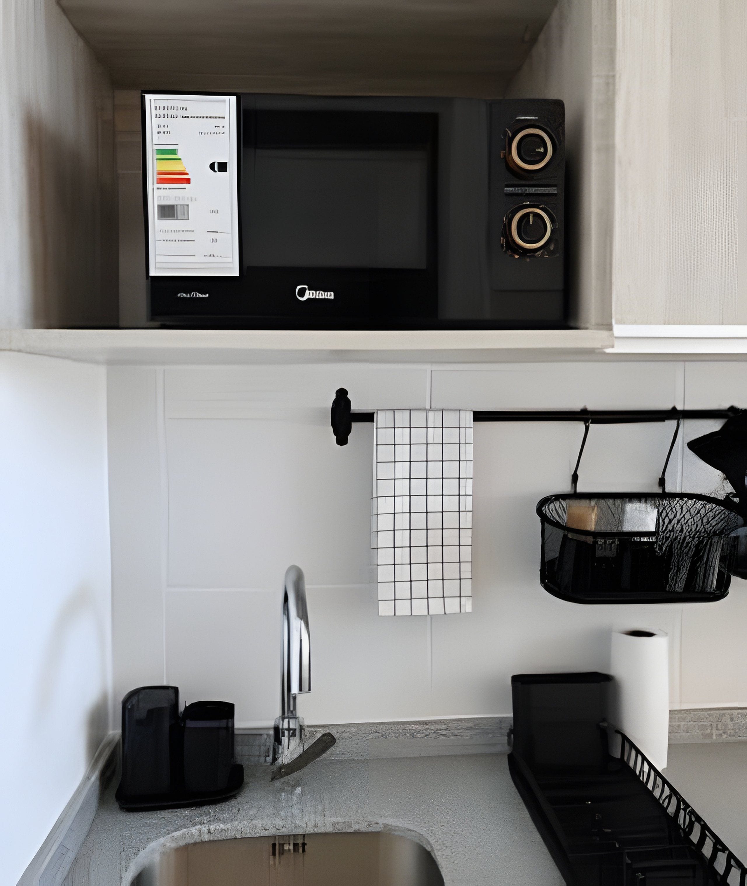 Una cocina con microondas, un lavabo y un tendedero.