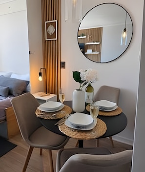 A dining area with a round table, two chairs, a vase with flowers, and a mirror on the wall. - Vista al mar - Estudio para 3 personas (Coquimbo)