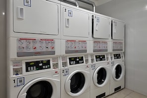 A row of white, multi-functional laundry machines with control panels and numbered compartments.