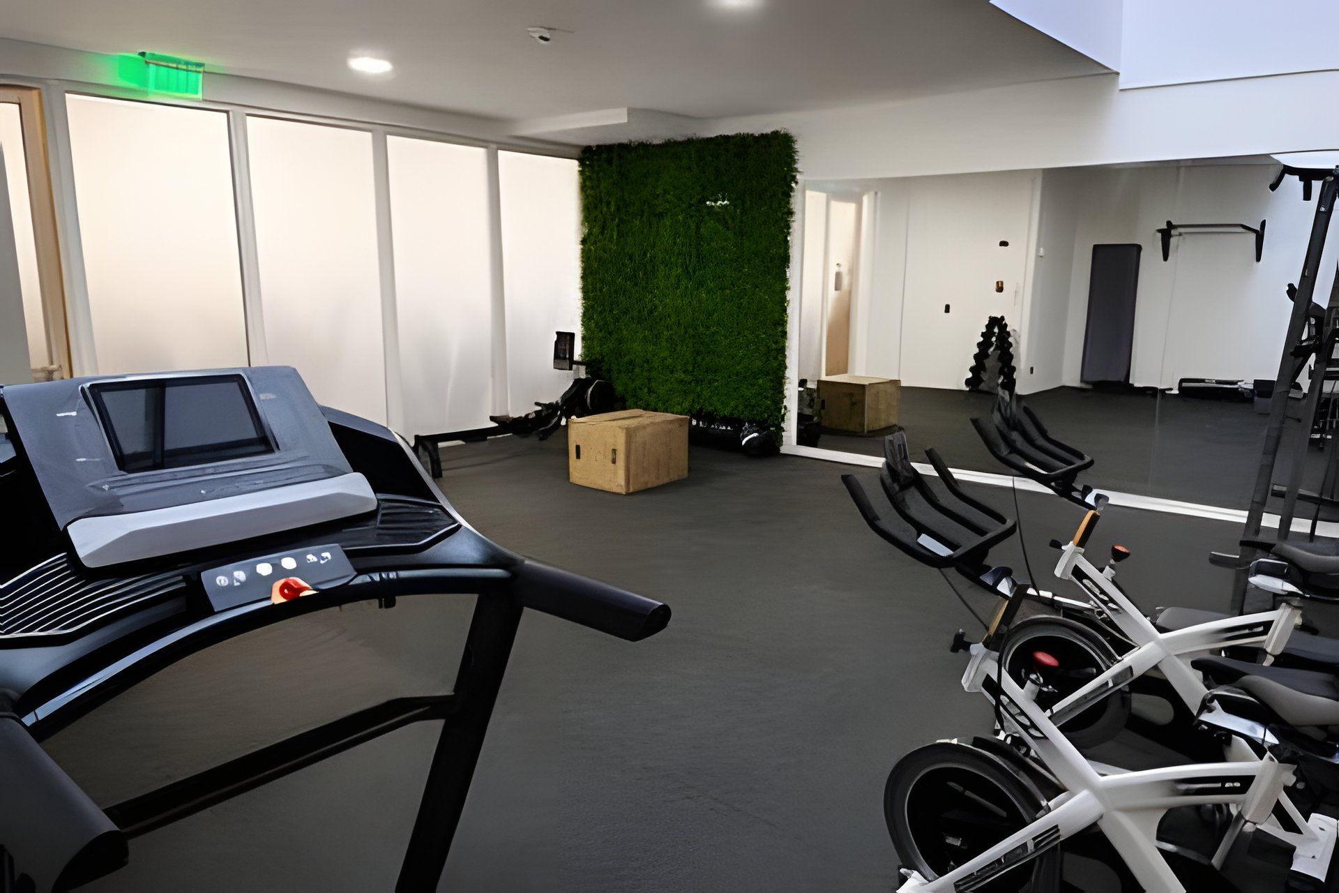 Un gimnasio con equipo de ejercicio, una cinta de correr y una pared verde.