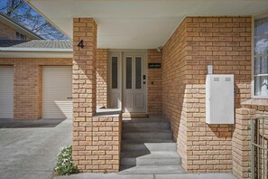 A brick exterior with a door, steps leading to a porch, and a utility box. - Long Beach Retreat - Stylish 3-bed beach side townhouse! (Sandy Bay)