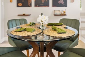 A round glass table with woven placemats and green napkins, surrounded by green upholstered chairs. - Mayo Clinic Cottage - Power Bed & Recliners (Rochester)
