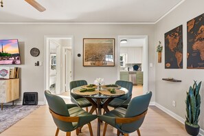 Un comedor con una mesa redonda, cuatro sillas y vista a la cocina.