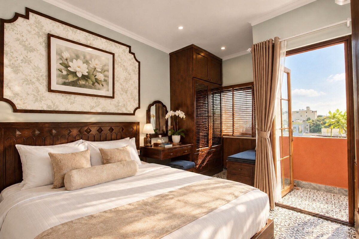 A hotel room with a large bed, a wooden headboard, a nightstand, a window with blinds, and a view of the city.