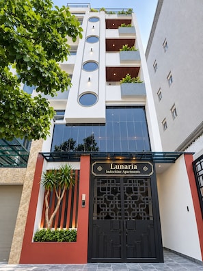 A modern building with a large black entrance gate, balconies with plants, and a sign for 'Lunaria Indochine Apartments'. - Lunaria Indochine Apartments (An Hai)