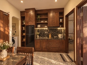 A compact kitchen with wooden cabinets, a black refrigerator, and a marble countertop. - Lunaria Indochine Apartments (An Hai)