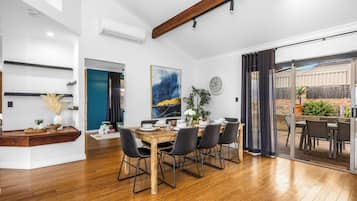 A modern dining area with a wooden table set for six, surrounded by chairs with metal frames.