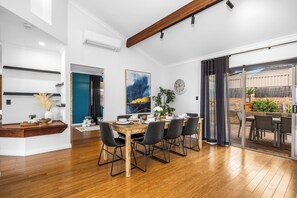Un espace repas moderne avec une table en bois dressée pour six personnes, entourée de chaises à structure métallique.