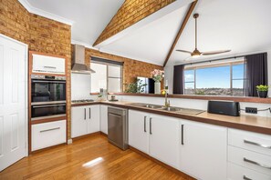 A modern kitchen with a brick wall, stainless steel appliances, and a view of the city.