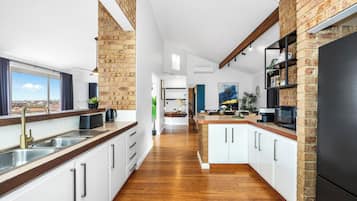 A modern kitchen with white cabinetry, a black refrigerator, and a view of the city through large windows.
