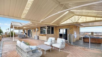 A covered outdoor patio with seating, a barbecue area, and a view of the city.